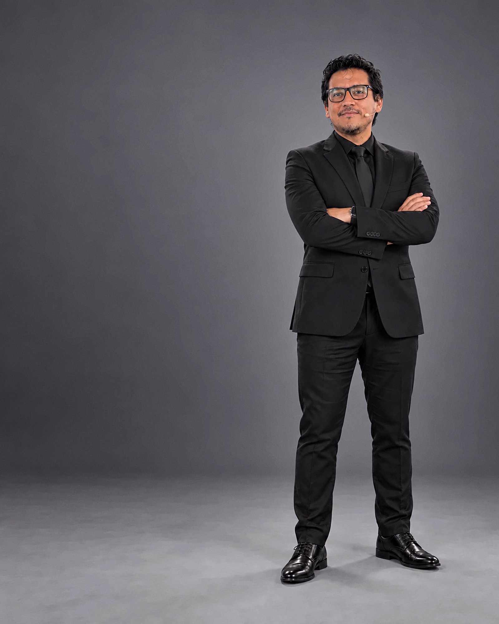 Leonardo Condori de pie, con traje, en estudio.